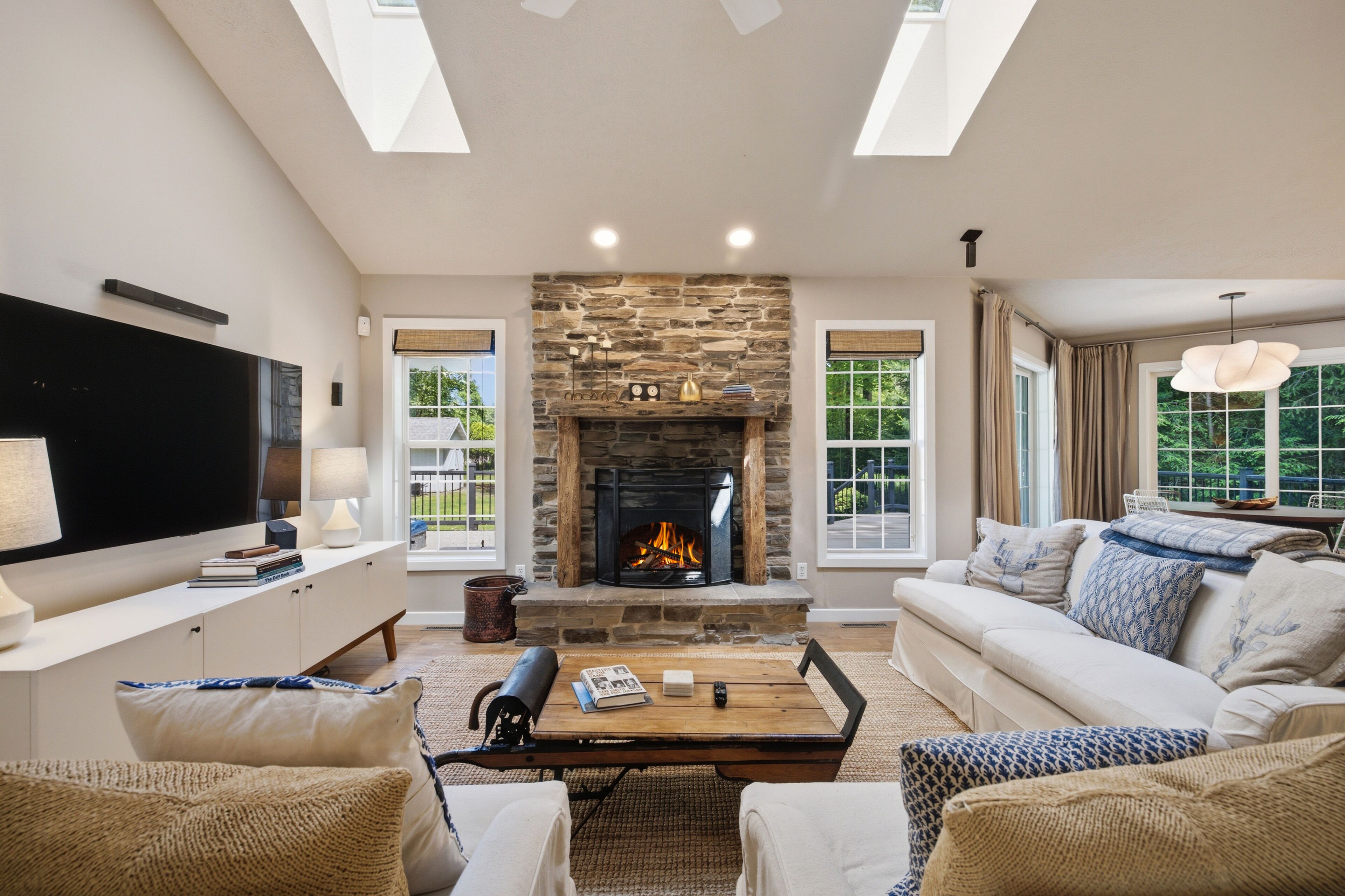A living room with a stone fireplace, a flat-screen TV, a sofa, and a coffee table.