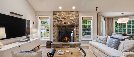 A living room with a stone fireplace, a flat-screen TV, a sofa, and a coffee table.