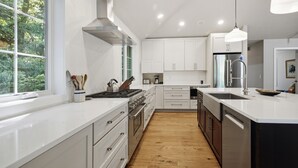 A modern kitchen with white cabinets, a stainless steel refrigerator, and a large window. - Union Pier Home Walking Distance To Beach With Hot Tub! (Union Pier)