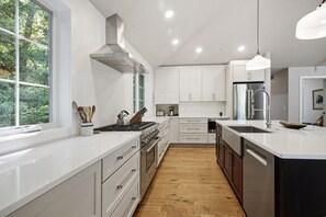A modern kitchen with white cabinets, a stainless steel refrigerator, and a large window. - Union Pier Home Walking Distance To Beach With Hot Tub! (Union Pier)