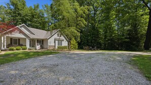 A house with a gravel driveway, a front porch, and a wooded area. - Union Pier Home Walking Distance To Beach With Hot Tub! (Union Pier)