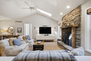 A living room with a fireplace, a ceiling fan, a flat-screen TV, and a sofa. - Union Pier Home Walking Distance To Beach With Hot Tub! (Union Pier)