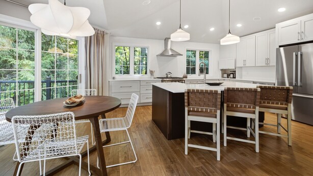 Une cuisine moderne avec des meubles blancs, un îlot central et des luminaires suspendus.