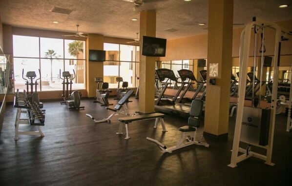 Un gimnasio con cintas de correr, elípticas y máquinas de pesas.