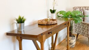 Een houten consoles van een gevlochten mand, een potplant en een kleine witte vaas.