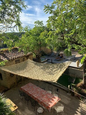 An outdoor patio with a thatched roof, a long table with chairs, and a hot tub.