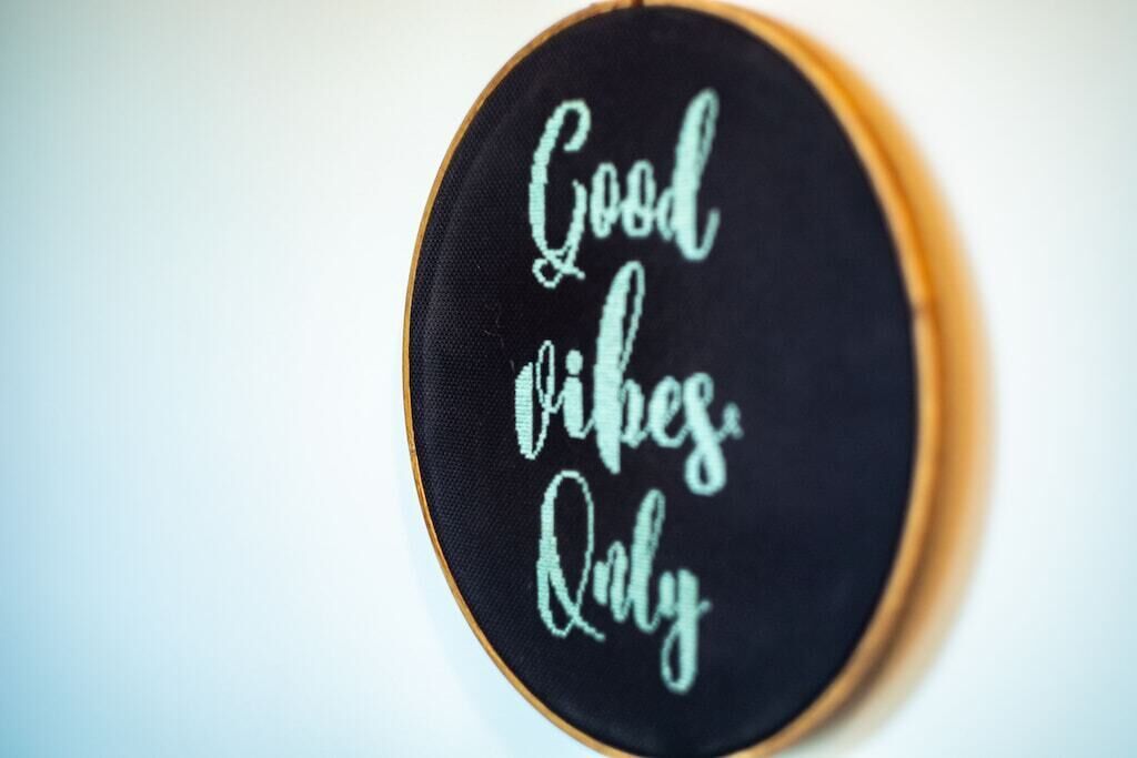 Een ronde borduursel met de tekst 'Good vibes only' op een zwarte achtergrond.
