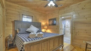 A wooden cabin bedroom with a bed, nightstand, and a ceiling fan. - Downtown Lodge Blue Ridge, sleeps 14,walk to strip (Blue Ridge)