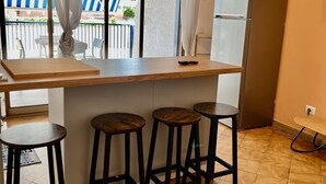 A kitchen with a wooden countertop, four stools, a refrigerator, and a window with curtains. - Beautiful, newly remodeled 1 bedroom -50 meters from the beach (Giardini-naxos)