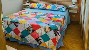 A bedroom with a bed, a window, an air conditioner, a painting, and a bedside table with a lamp. - Beautiful, newly remodeled 1 bedroom -50 meters from the beach (Giardini-naxos)