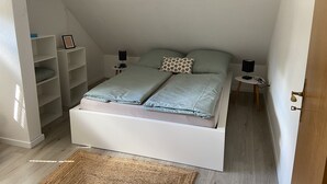 Ett litet, väl upplyst sovrum med en enkelsäng, två sängbord och en inbyggd hyllsektion.