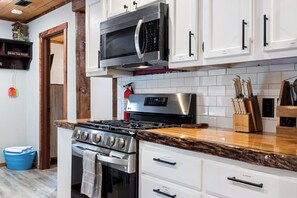 Kitchen equipped with a stove, microwave, and knives.
