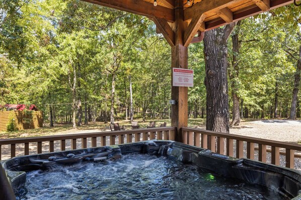 Relax in a serene hot tub under a shaded pergola surrounded by lush greenery.