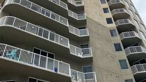 A tall, modern high-rise building with multiple balconies and windows.