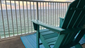 A green chair on a balcony with a view of the ocean.