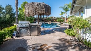 A backyard with a barbecue, a swimming pool, and a house.