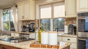 A modern kitchen with a granite countertop, stainless steel appliances, and a large window providing natural light.