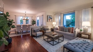 A modern living room with a sofa, chairs, a coffee table, and a dining area.