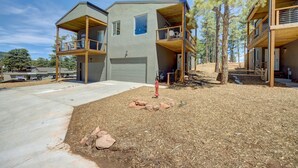 A modern two-story house with a covered porch, a garage, and a small outdoor area with rocks and a tree.
