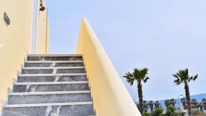 A staircase with marble steps leading up to a building with a yellow facade. - Lambisea 2 Bedroom Apartment (Kos)