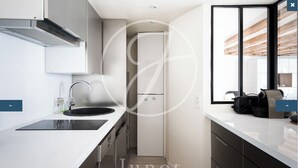 A modern kitchen with a black sink, stainless steel faucet, and a built-in oven. - Charming apartment in the heart of Saint-Germain (Paris)