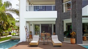 Un bâtiment moderne à deux étages doté d’un espace piscine comprenant des chaises longues et une table.