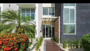 Un bâtiment moderne à deux étages, doté d’une entrée couverte, d’une enseigne portant le chiffre « 4 » et d’un jardin bien entretenu agrémenté de fleurs rouges et de plantes vertes.