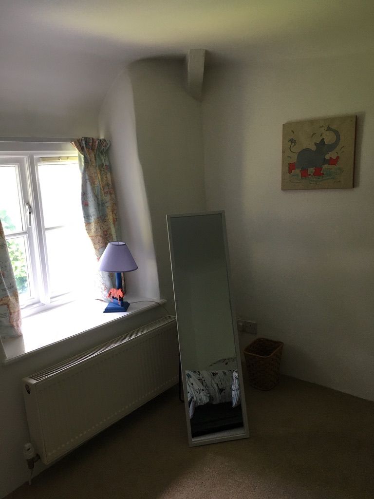 A room with a radiator, a window with curtains, a lamp, and a painting on the wall.