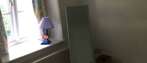 A room with a radiator, a window with curtains, a lamp, and a painting on the wall.