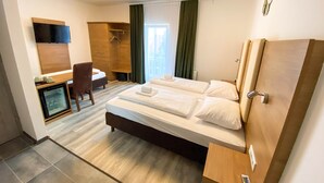 Habitación de hotel con cama, escritorio, silla, televisor y armario.