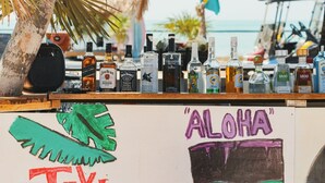 Een bar met diverse drankflessen en een bord waarop 'ALOHA' staat.