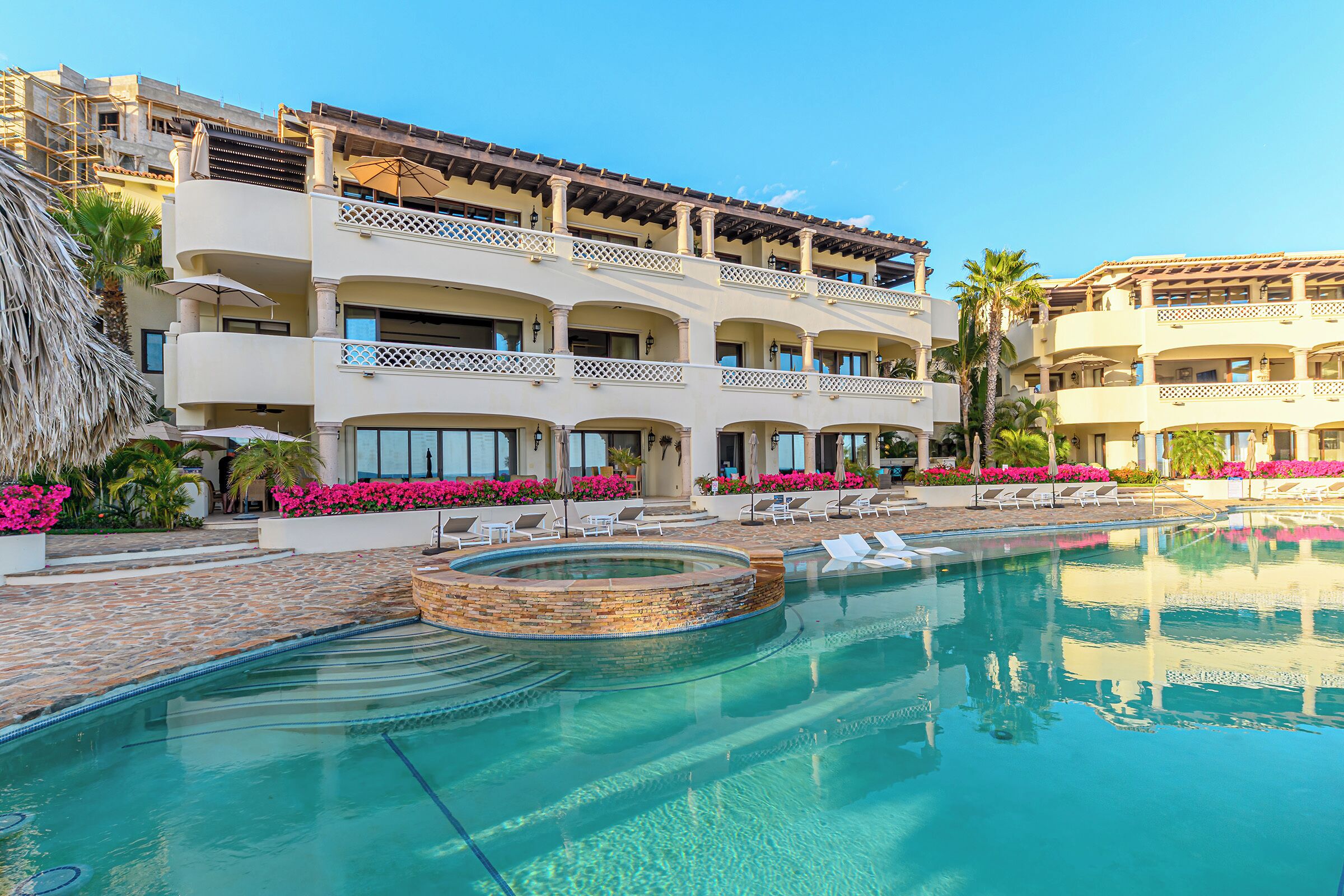 A hotel with a swimming pool, multiple balconies, and outdoor seating areas.