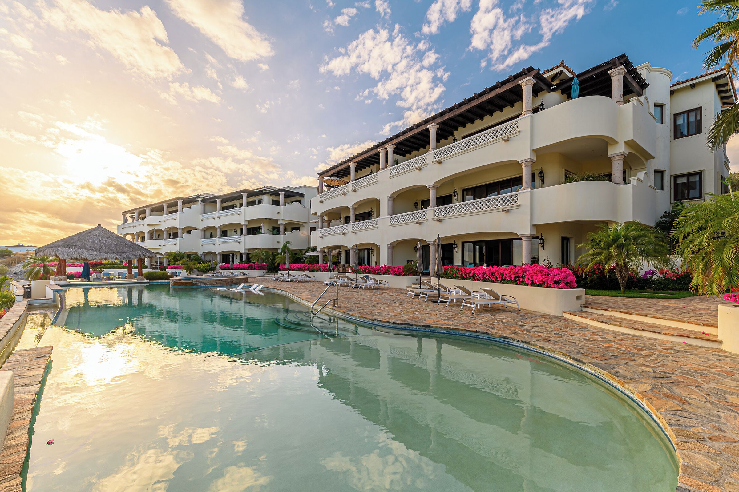 Ein Resort mit Schwimmbad, mehreren Balkonen und einem tropischen Garten.
