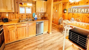Une cuisine de style rustique, avec des éléments en bois, comprenant un îlot central, un évier et un coin repas avec une table et des chaises.
