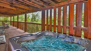 Un bain à remous situé sous une terrasse en bois, avec vue sur les arbres.