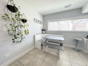Een compacte, moderne keuken met een witte werkbank, een raam met zonwering en een hangplant.