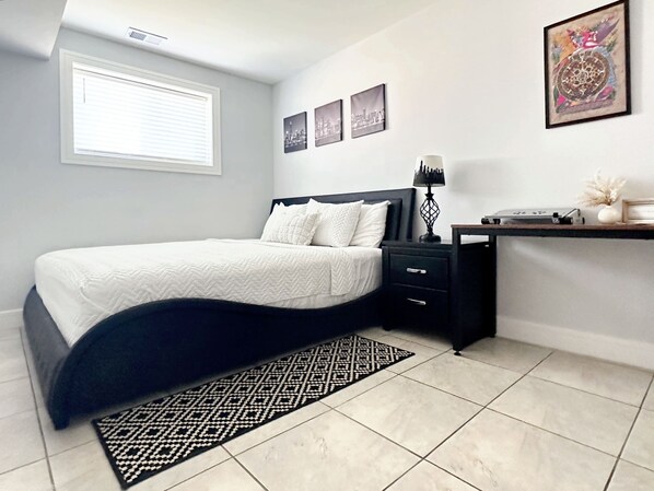 Un dormitorio con cama, mesita de noche, lámpara y decoración en la pared.