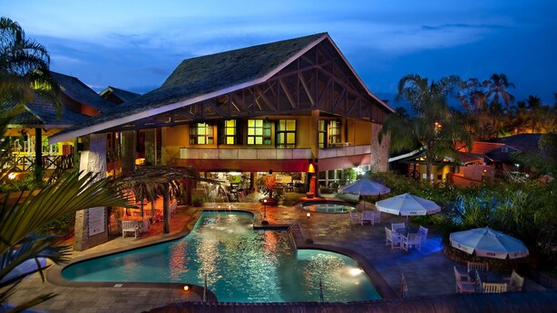 A resort with a large pool, outdoor seating, and a well-lit building. - Ilha Flat Hotel (Ilhabela)