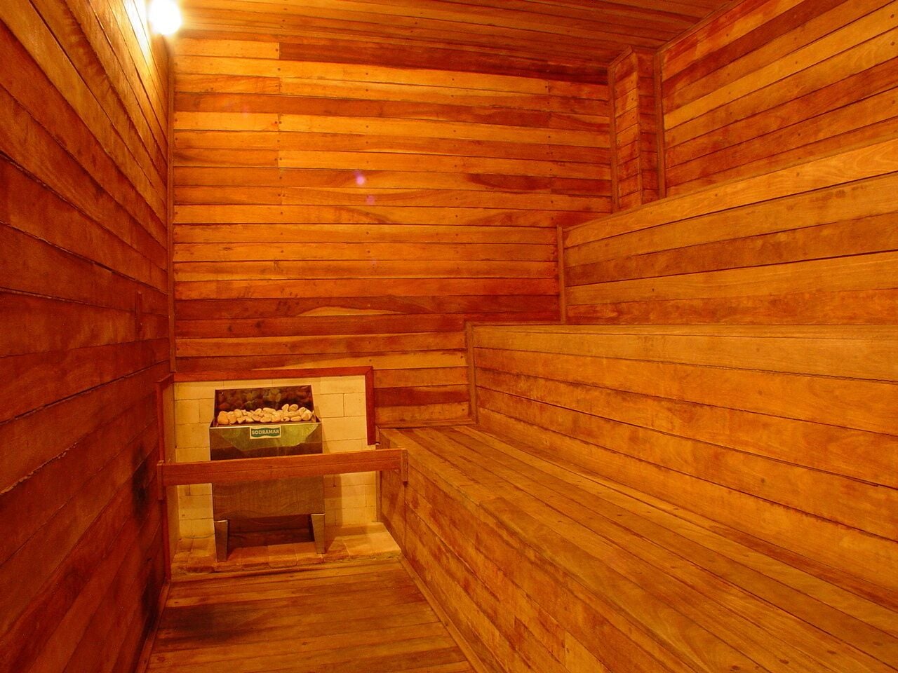 A wooden sauna with benches and a bench with a box of products.