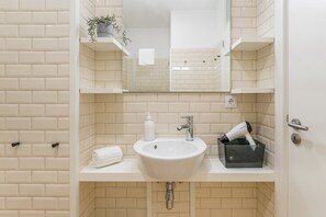 A bathroom with a white sink, a mirror, and a towel on the counter.