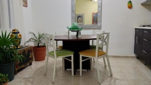 Uma sala de jantar com mesa redonda, duas cadeiras, uma planta em vaso e um espelho na parede.