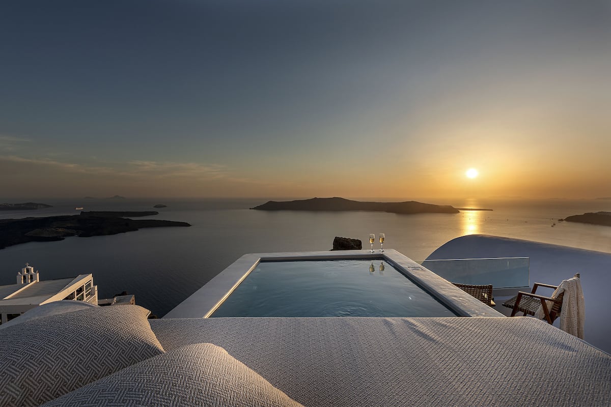 Une piscine à débordement offrant une vue sur la mer et le coucher de soleil.