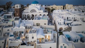 A white building with a blue dome and a bell tower. - Kaleidoscope Imerovigli Suites (Santorini)
