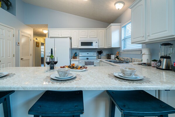 A kitchen with white cabinets, a marble countertop, and a central island with stools.