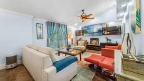 A living room with a beige sofa, a red armchair, a coffee table, and a TV mounted on the wall. - Welcome to the Farm House! Excellent Location, Pet Friendly! (Windermere)