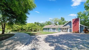 A residential house with a paved driveway, a garage, and a red garage door. - Welcome to the Farm House! Excellent Location, Pet Friendly! (Windermere)