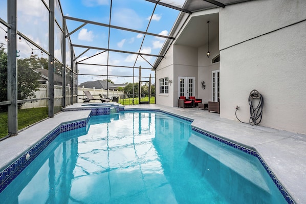 Une piscine dotée d’une enceinte en verre, un patio couvert et une vue sur le paysage environnant.