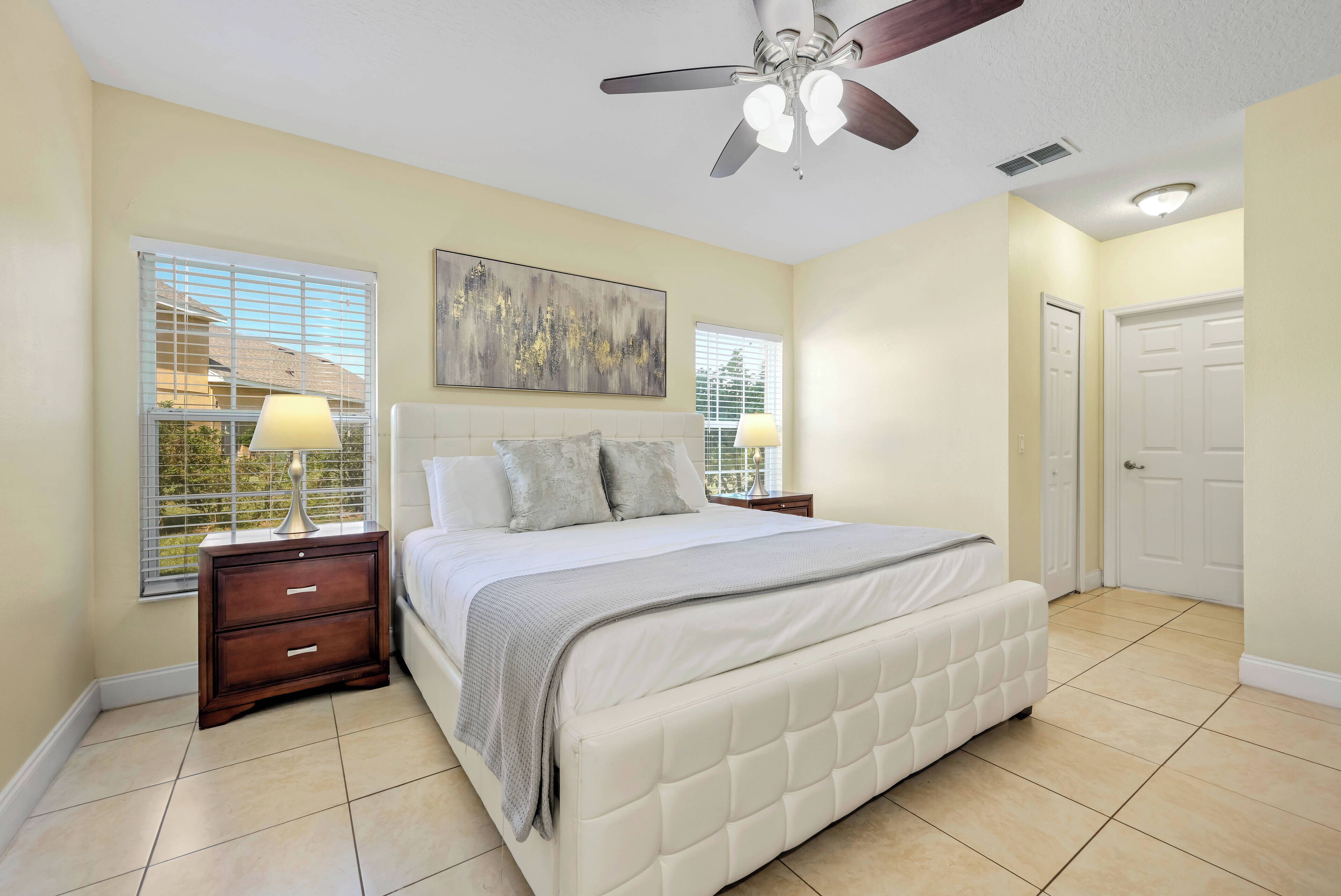 A bedroom with a bed, nightstands, a ceiling fan, and a window with blinds.