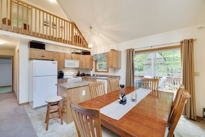 A spacious kitchen with wooden cabinets, a central island, and a dining area with a wooden table and chairs. - Chalet w/ firepit, deck, BBQ, fireplace, Wi-Fi, AC, close to waterparks, skiing (Pocono Lake)