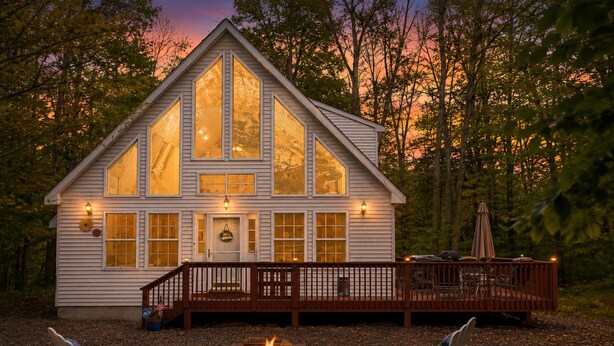 A cabin with large windows, a deck, and a fire pit. - Chalet w/ firepit, deck, BBQ, fireplace, Wi-Fi, AC, close to waterparks, skiing (Pocono Lake)
